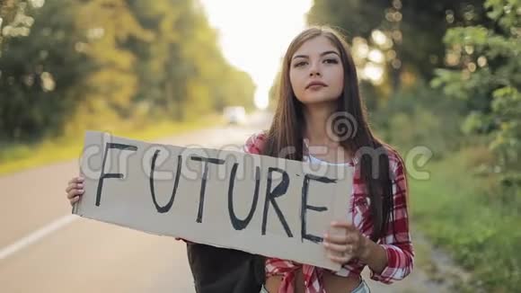 年轻漂亮的女人搭车站在路上举着未来的标志夏季视频的预览图