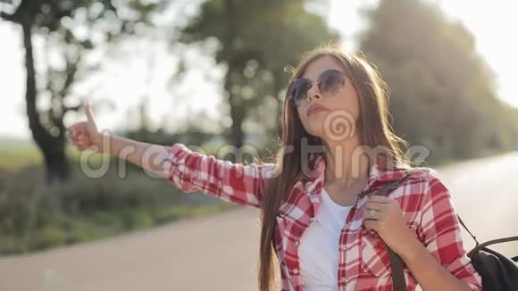 旅行者年轻的女人在阳光明媚的路上搭便车年轻女孩想搭车开始一段旅程夏季视频的预览图