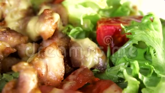沙拉与蔬菜和肉片围绕着它的轴线在一个白色的盘子在一个黑色的背景特写视频的预览图