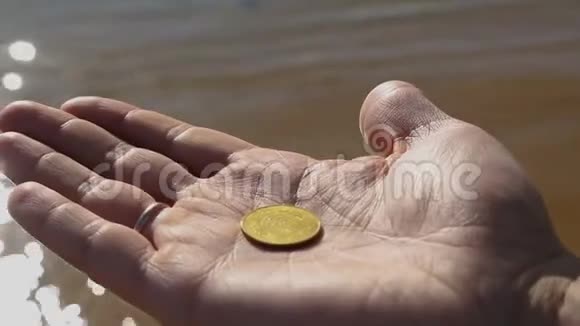 男性游客手持硬币用停泊的船只将硬币扔进小海湾视频的预览图