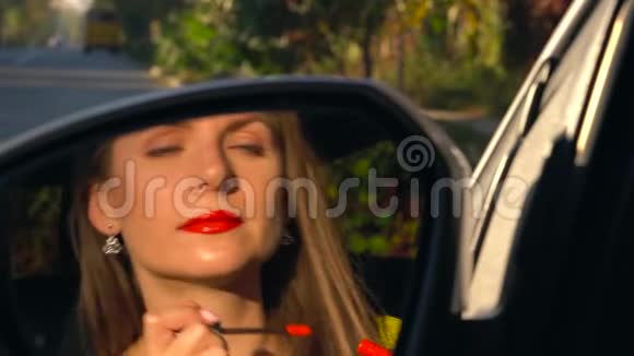 女人用红色口红涂嘴唇看着后视镜视频的预览图