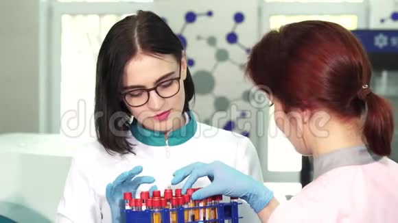 漂亮的女化学家和她的助手在试管里工作视频的预览图