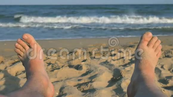 人的脚在沙滩上晒日光浴沙滩上有海浪人的脚在沙滩上裸着视频的预览图