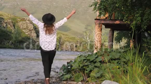 漂亮的深色头发戴着帽子穿着白衬衫穿着豌豆在山上享受着大自然年轻的女游客散步视频的预览图