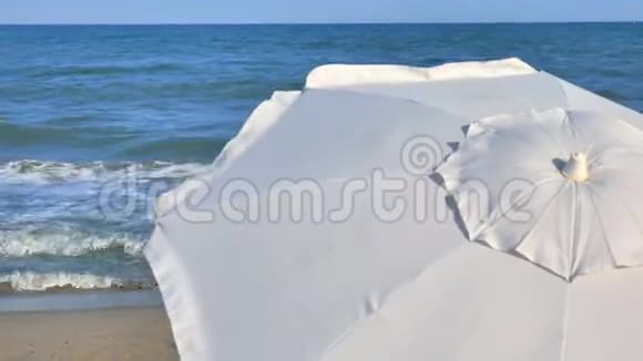 阳光明媚的一天海滩上有白色的雨伞和蓝色的大海视频的预览图