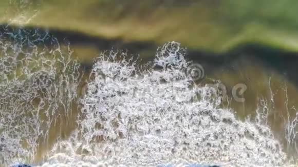 西班牙海滩的鸟瞰海浪来到海岸在海岸外形成泡沫和气泡他的表情视频的预览图