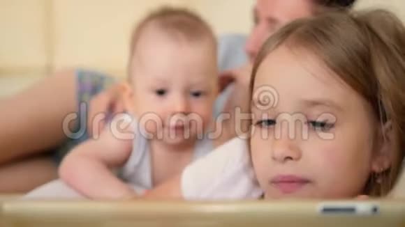 家庭观念姐姐和弟弟在房间的沙发上用平板电脑充满爱意的家庭年轻母亲视频的预览图