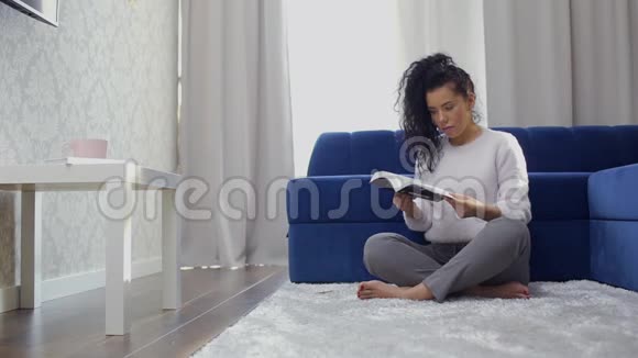 一位美丽的白种人黑发女郎正坐在地上翻书视频的预览图