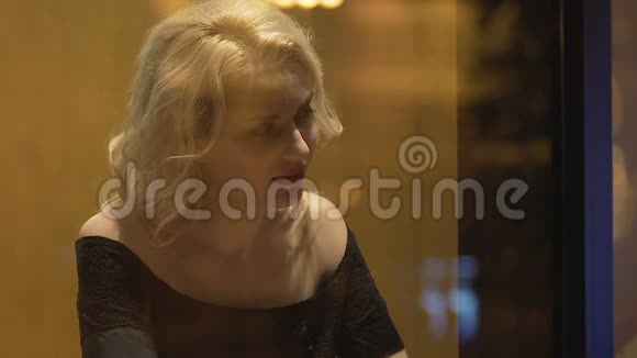 迷人的金发女人独自坐在酒吧桌旁寻找男人调情视频的预览图