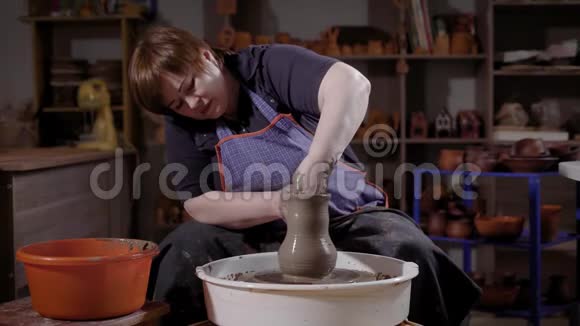一个年轻的女人学会制作粘土制品学生用陶工轮子和陶器材料制作视频的预览图