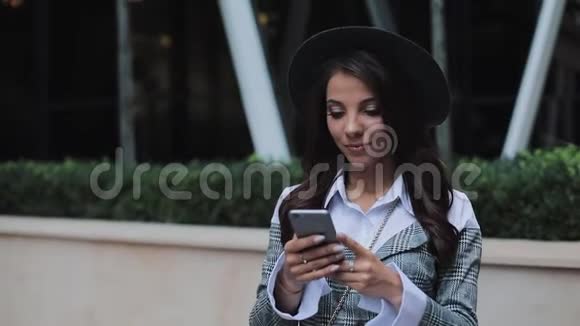 专业的年轻商务女士站在城市街道上使用智能手机她看着摄像机概念视频的预览图