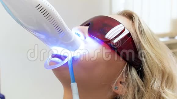 牙齿美白过程中躺在牙科椅上的金发年轻女子特写4k视频视频的预览图