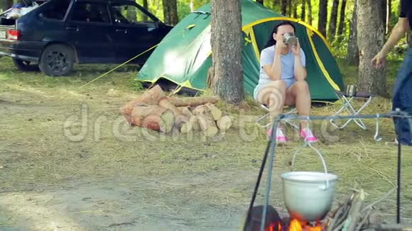 一男一女坐在帐篷旁喝着茶看着锅子挂在火堆上视频的预览图