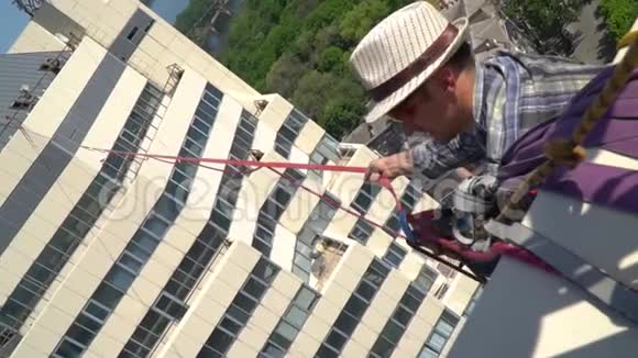 那人为从大楼上挂下来的那根高绳准备绳子视频的预览图