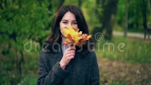 秋天公园里一位年轻女子在她的脸上挥舞着枫叶视频的预览图