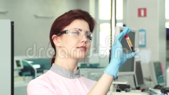 年轻的女性生物学家检查两支试管的血液视频的预览图