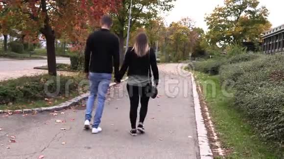 一个女孩和一个男人走在秋天的小巷里视频的预览图