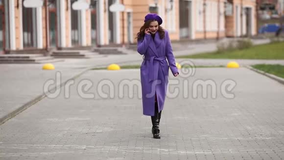 穿紫色外套的时髦女人在街上打电话视频的预览图