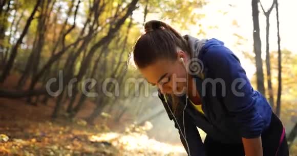 公园里的女跑步者阳光明媚劳累的穿健身服的年轻女子长时间休息后的特写镜头视频的预览图