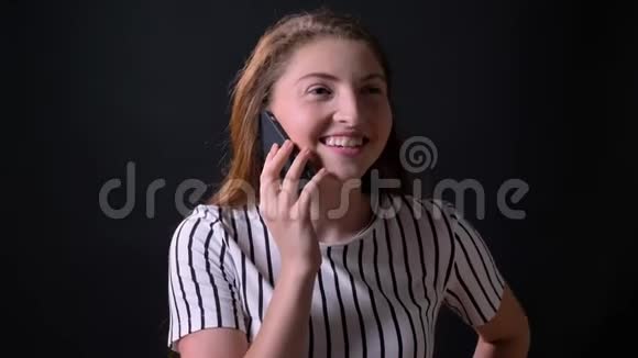 美丽开朗的姜女在电话里交谈微笑着站在黑工作室的背景上视频的预览图