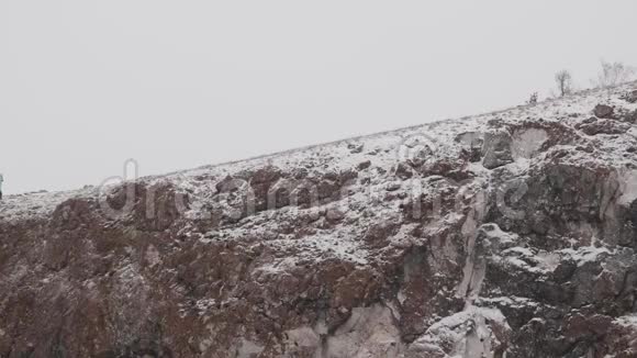 年轻女子徒步旅行者在冬季徒步旅行中爬上山坡视频的预览图