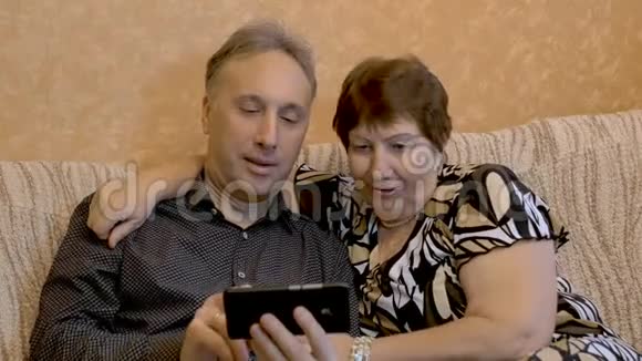 一位老妇人和她成年的儿子正在智能手机上观看他们家庭的照片视频的预览图