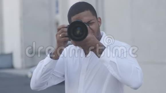 非洲裔美国摄影师在城市背景下用相机在室外拍照视频的预览图