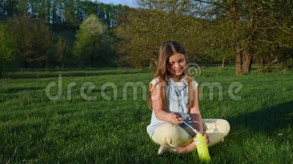 女孩在春天公园吹肥皂泡慢动作视频的预览图