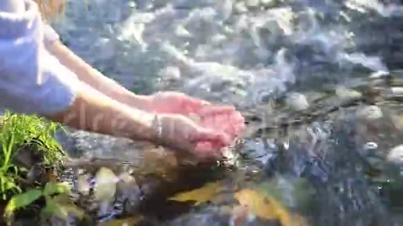 女人手在瀑布清澈的水中视频的预览图