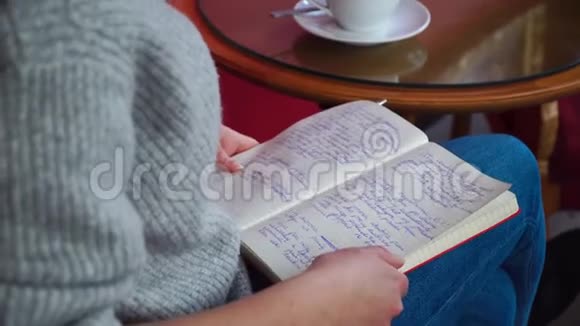 坐在桌旁拿着记事本喝咖啡的女孩视频的预览图