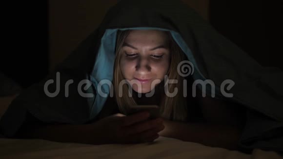 夜晚黑暗可爱的女人使用手机躺在床上视频的预览图