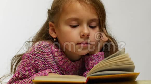 一个女孩读一本书的特写镜头一个年轻可爱的女孩低声读一本书视频的预览图