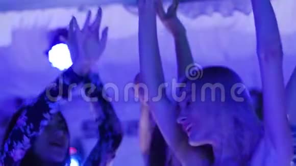 一群举着双手的年轻女子在夜总会的舞池闲逛视频的预览图