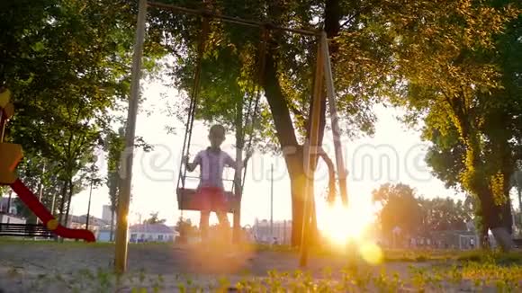 微笑的小女孩在金色的夏日夕阳下摇摆着在公园里在树林里在大自然里温暖的夏日视频的预览图