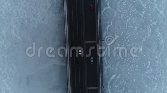 冬天的一天繁忙的桥在冰冻的河流上垂直的空中拍摄视频的预览图