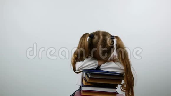 一年级的女孩坐在书上神情疲惫一个疲惫的学生带着书看着摄像机视频的预览图