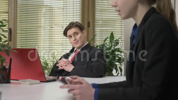 穿西装的年轻人坐在办公室里一个对话和一个下属的女人与女孩调情办公室的工作视频的预览图