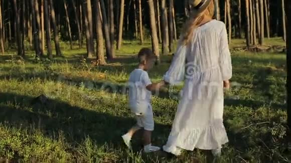 小男孩和妈妈一起走在绿色的田野上手牵着手慢动作视频的预览图