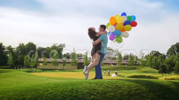 慢动作视频快乐快乐的年轻夫妇拿着五颜六色的气球在公园玩得开心视频的预览图