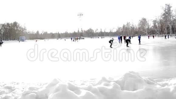 一群滑冰运动员在体育场冬季公园的露天溜冰场训练视频的预览图