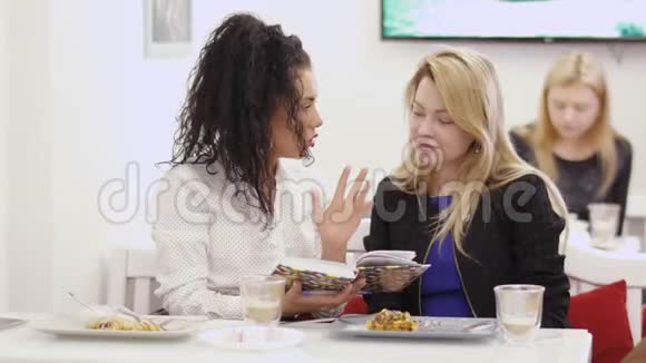 两位年轻妇女在咖啡馆里讨论和规划未来的假期视频的预览图