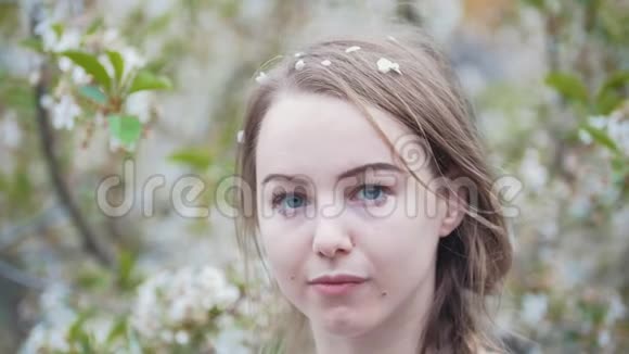 花园里年轻女子的肖像女孩在她的头发上扎了一枝紫丁香视频的预览图