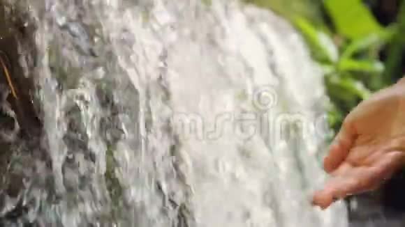 丛林雨林中的女性手触清新自然的春天瀑布4K慢动作印度尼西亚巴厘视频的预览图