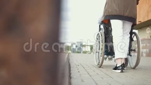 年轻女子与残疾人坐轮椅在街上行走视频的预览图