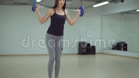 漂亮的黑发女人在健身房里用杠铃做冲刺视频的预览图