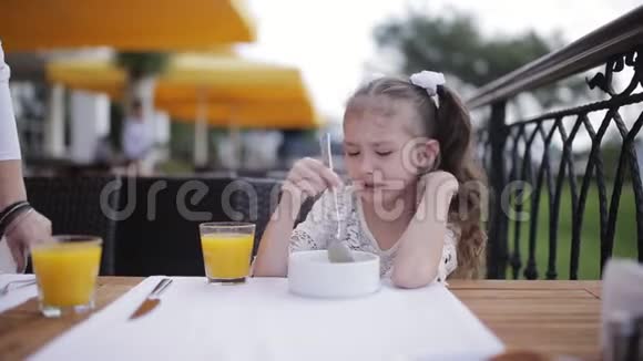 妈妈在户外餐馆里喂淘气的女孩汤视频的预览图