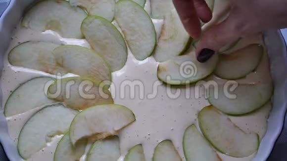 女人做苹果派厨师把苹果片放进烤盘里在烤盘的蛋糕面糊上切苹果甜食视频的预览图