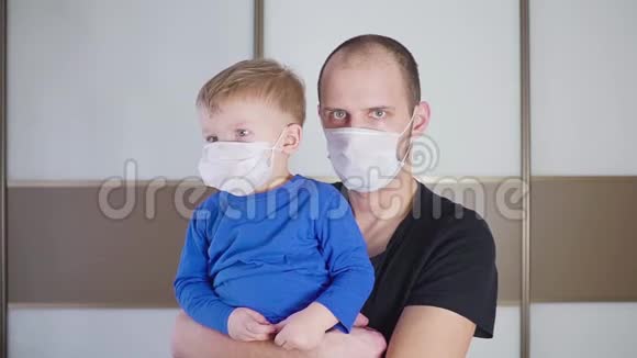父亲抱着可爱的小婴儿婴儿的肖像孩子戴着保护性医疗面具爸爸和儿子站在里面视频的预览图
