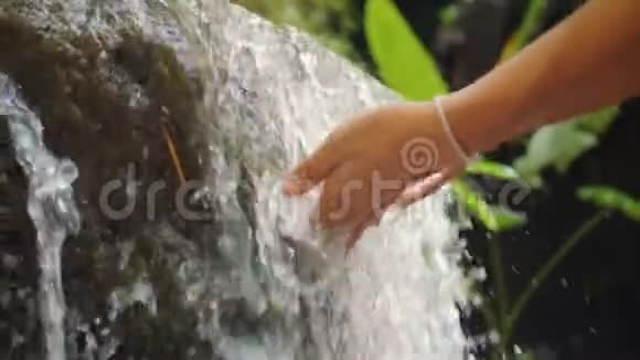 丛林雨林中的女性手触清新自然的春天瀑布4K慢动作印度尼西亚巴厘视频的预览图