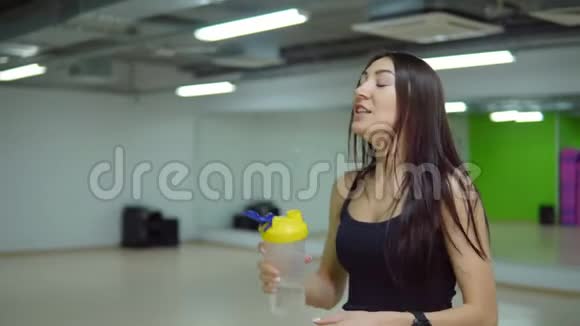 穿运动制服的年轻女子在健身房喝水视频的预览图